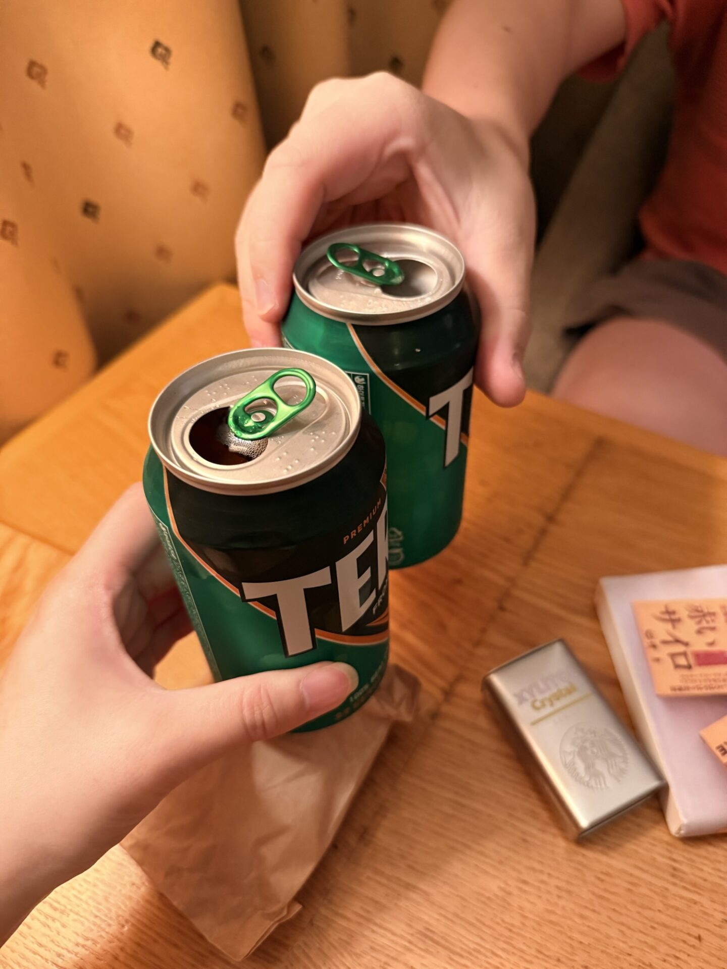 ホテルの客室でテラビールの缶を持って乾杯する様子